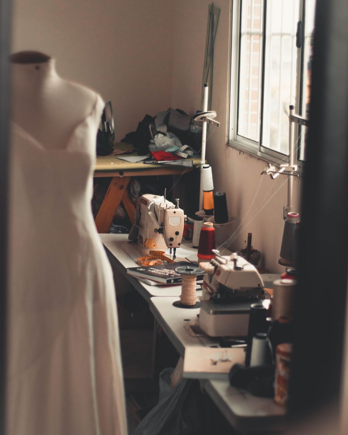 Atelier-Ambiente: Schneiderpuppe mit Kleid und Nähmaschinen am Fenster